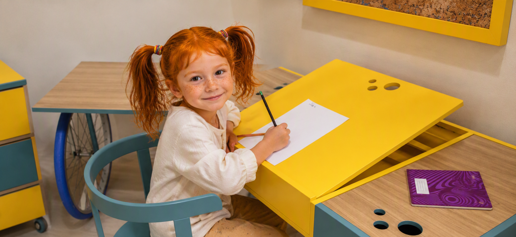 Girl writing at a yellow MAMA developmental desk with built-in storage
